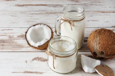 Hindistan cevizli vejetaryen sütü ve hindistan cevizli tereyağı ve beyaz ahşap masa. Vejetaryen hindistan cevizi sütü ve tereyağı.