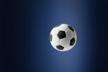 Geleneksel futbol topu mavi arka planda uçuyor. Tasarım için futbol arkaplanı.