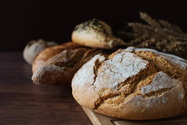 Loaf of sourdough bread with crispy crust on wooden background. Healthy organic bakery goods.