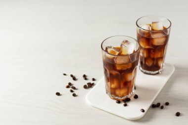 Beyaz ahşap masada iki bardak buzlu kahve. Yaz içeceği..