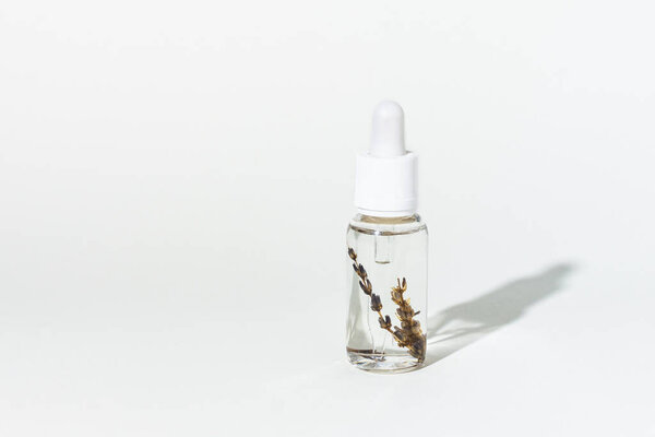 Droplet bottle of cosmetic lavender oil for skin care on white background with shadow. Hydrating herbal serum, vitamin for face skin.