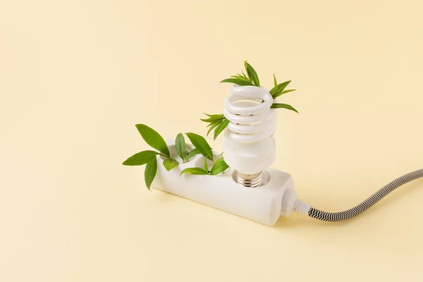 White plug and light bulb with green plant as a concept of eco energy. Creative idea of eco alternative energy.