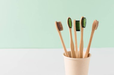 Yeşil duvarın üzerinde çevre dostu bambu diş fırçaları. Sıfır atık hijyen ürünleri kavramı. Diş bakımı ekipmanları.