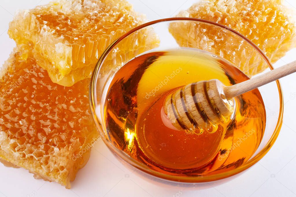 Sweet honey and honeycomb. Healthy organic honey in a bowl and wooden honey dipper. Sweet healthy dessert.