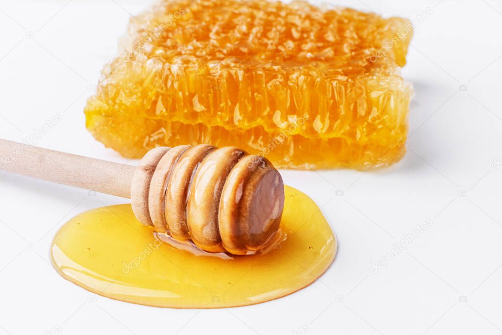 Sweet honey and honeycomb. Healthy organic honey, slices of honeycomb and wooden honey dipper isolated on white background. Sweet healthy dessert.