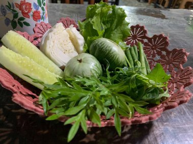 Dilimlenmiş salatalık, fesleğen, patlıcan, lahana ve ahşap tabakta uzun fasulyeler dahil çeşitli taze sebzeler. Sağlıklı gıda konsepti.