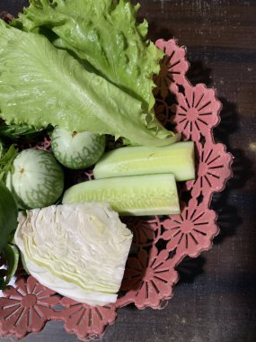 Dilimlenmiş salatalık, fesleğen, patlıcan, lahana ve ahşap tabakta uzun fasulyeler dahil çeşitli taze sebzeler. Sağlıklı gıda konsepti.