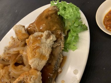 Domates, marul, dolmalık biber, sarımsak ve beyaz tabakta Tamarind soslu acılı gourami balığı. Tayland geleneksel yemek tarzı..