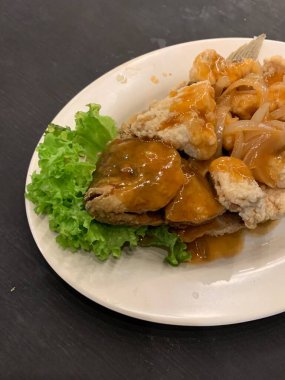 Domates, marul, dolmalık biber, sarımsak ve beyaz tabakta Tamarind soslu acılı gourami balığı. Tayland geleneksel yemek tarzı..