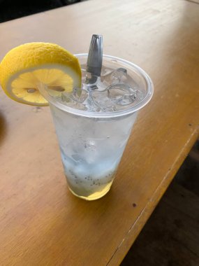 Bir bardak buzlu soda ve üstüne bir dilim limon. Tahta masanın üzerine serinletici bir dokunuş ekleyin. Tropik içki konsepti.