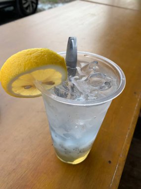 Bir bardak buzlu soda ve üstüne bir dilim limon. Tahta masanın üzerine serinletici bir dokunuş ekleyin. Tropik içki konsepti.