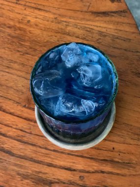 Kurumuş narenciye garnitürlü dokuma bardakta servis edilen canlı mavi kokteyl. İçki ferahlatıcı gibi görünüyor, muhtemelen alkolsüz moktail içeriyor limonata gibi..