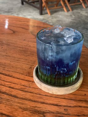 Kurumuş narenciye garnitürlü dokuma bardakta servis edilen canlı mavi kokteyl. İçki ferahlatıcı gibi görünüyor, muhtemelen alkolsüz moktail içeriyor limonata gibi..