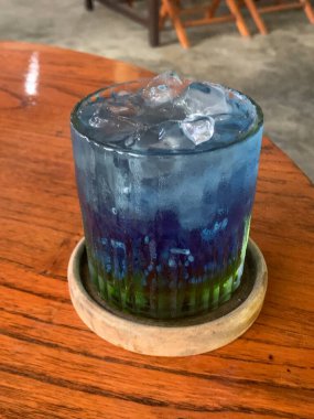 Kurumuş narenciye garnitürlü dokuma bardakta servis edilen canlı mavi kokteyl. İçki ferahlatıcı gibi görünüyor, muhtemelen alkolsüz moktail içeriyor limonata gibi..