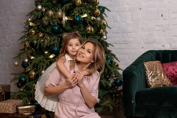 Merry Christmas and Happy Holidays. The family decorates the holiday tree. Mother and daughter decorate the Christmas tree. Happy mother giving a Christmas present. New Year