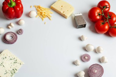 Beyaz arka planda ev yapımı pizza için gerekli malzemeler. Pişirme ürünleri: domates, tatlı biber, mantar, peynir, soğan. Beyaz arkaplanda kopyalama alanı olan üst görünüm. Yakın plan..