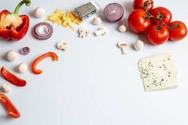 Beyaz arka planda ev yapımı pizza için gerekli malzemeler. Pişirme ürünleri: domates, tatlı biber, mantar, peynir, soğan. Beyaz arkaplanda kopyalama alanı olan üst görünüm. Yakın plan..