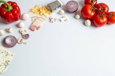 Beyaz arka planda ev yapımı pizza için gerekli malzemeler. Pişirme ürünleri: domates, tatlı biber, mantar, peynir, soğan. Beyaz arkaplanda kopyalama alanı olan üst görünüm. Yakın plan..