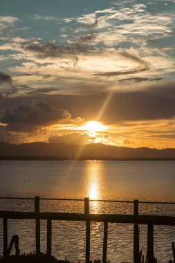 Su ve Uzak Dağlar Üzerinde Manzaralı Gün Batımı