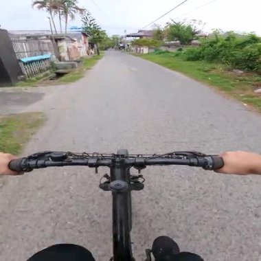 Dar bir yolda bisiklete binmek. Öğleden sonra Gorontalo şehrinin sokaklarında bir bisikletçinin POV 'u