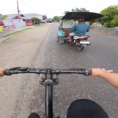 Şehir sokağında bisiklete binmek. Öğleden sonra Gorontalo şehrinde bir bisikletçinin POV 'u ve yağmur nedeniyle yol koşulları ıslak