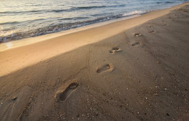 Günbatımında bir plajda ayak izleri