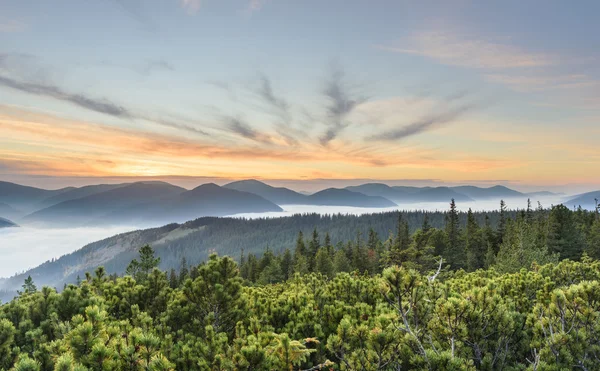 Una puesta de sol con niebla en las montañas — Foto de Stock