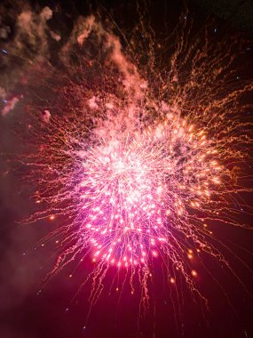Havai fişekler gece gökyüzünü aydınlatıyor. Parlak patlamalar ve parlak izler etkileyici bir görüntü yaratır..