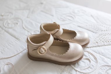 Beyaz dantelli yatak örtüsüne uzanmış vaftizde, düğünde ya da özel törende giyilecek ayakkabılar..