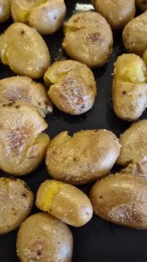 Kavrulmuş Portekiz patatesi, zeytinyağı, tuz ve biberiye ile baharatlı metal tepside, çıtır çıtır altın deriler ve kabarık iç kısımlar sağlıklı yan yemek konforu için..