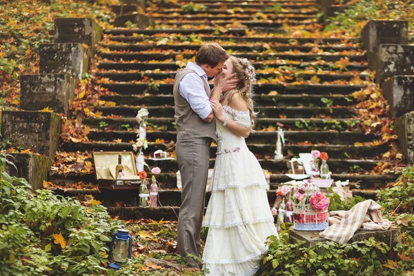 Wedding couple in a rustic style kissing near the stone steps surrounded by wedding decor — Stock Photo, Image