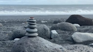 İzlanda Kara Kum Sahili 'nde Düşen Dalgalarla Dengeli Taş Cairn. Yüksek kalite 4k görüntü
