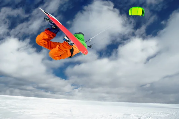 The sportsman on a snowboard runs kite