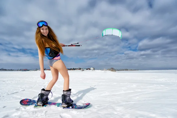 En smal flicka i en baddräkt på vintern. Snowboard och — Stockfoto