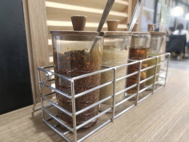 Baharat kavanozu şeker kavanozu çeşni, cam kap, ahşap kapak, metal kafeterya masası örtüsü.