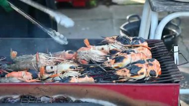 Izgara karides sokak yemekleri mangal kömürü üzerinde ızgara ve açık hava pişirme el Tong yakın yakın çekim taze kullanarak