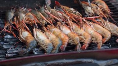 Izgara karides ızgarası sıcak kömür ızgarası alevli sokak yemeği açık havada taze kabuklu deniz hayvanı.