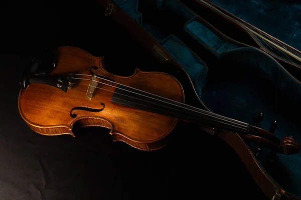 Eski keman siyah bir bezle kaplı bir masanın üzerine yerleştirilmiş.