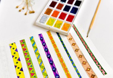 Masadaki suluboya ve fırçalar, soldaki küçük kaplarda parlak su rengi boya, küçük fırça, sanatçı masası sırasıyla.