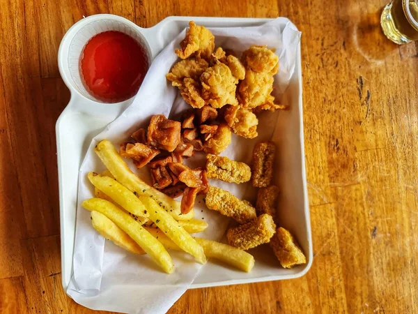 Baştan çıkarıcı patates kızartmaları, sosis, kızarmış tavuk ve sosla dolu bir tepsi. Fast food seçeneklerini sergilemek için ideal..