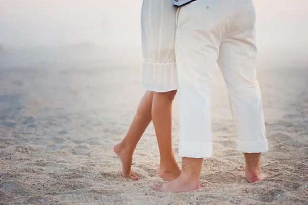 Casal amoroso em roupas brancas stand à noite na areia — Fotografia de Stock