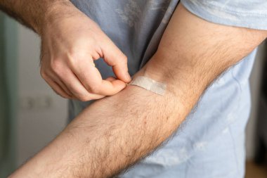 Erkek, yumuşak ışıkla sıcak ev ortamında koluna bandaj uyguluyor. Boşluğu kopyala