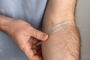 Erkek, deri dokusunu ve bakımını vurgulamak için koluna bandaj uyguluyor. Boşluğu kopyala