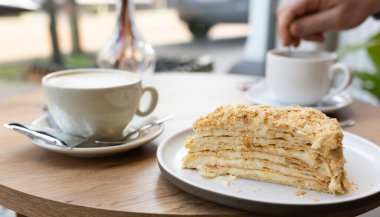 Masadaki kahve fincanlarının yanına katmanlı kek dilimi konmuş. yakın çekim, boş alan