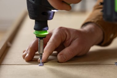 Kablosuz tornavida kullanarak yonga mobilyalarını monte etmek. Çizgili mobilya, görünür araç ve yüzey detaylarını monte etmek için tornavida kullanarak el kapatma