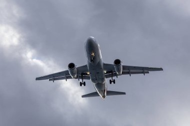 Uçaklar aşağıdan bulutlu bir gökyüzüne doğru uçuyor, kanatları ve iniş takımlarını dinamik bir hava perspektifinde vurguluyor.