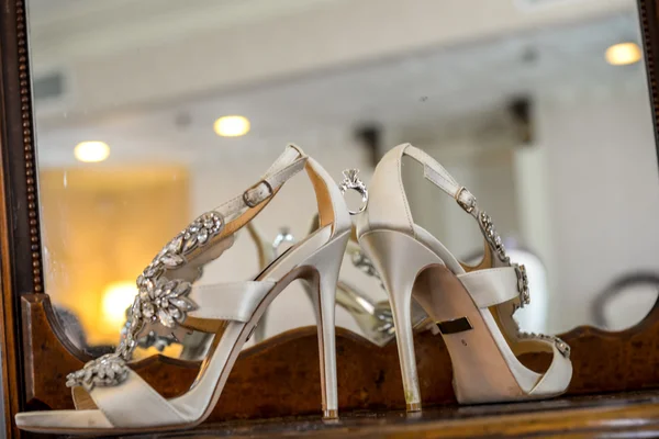 Wedding rings between bride's white shoes — Stock Photo, Image
