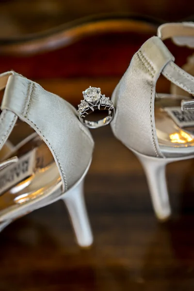 Trauringe zwischen weißen Schuhen der Braut — Stockfoto