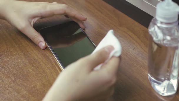Frau putzt Smartphone mit Feuchttuch an Holztisch — Stockvideo