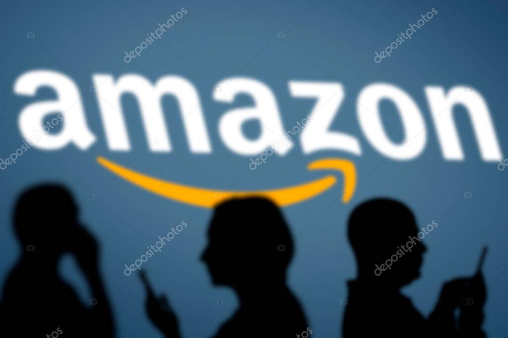 Tashkent, Uzbekistan - March 4, 2021: Silhouette of people over American multinational technology company Amazon logotype